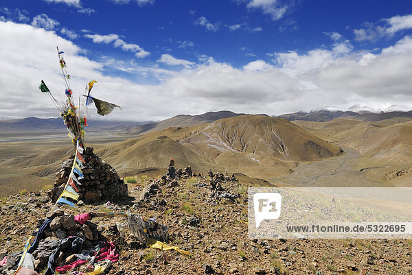 Steinhaufen mit Gebetsfahnen  Tingri Hochebene  hinten verschneite Berggipfel in tiefhängenden Wolken  Himalaya  Tibet  China  Asien
