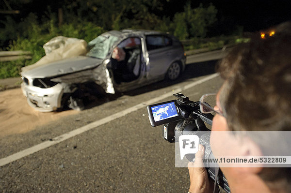 Blaulichtreporter  Kameramann filmt Wrack eines durch Verkehrsunfall zerstörten BMW  Remseck  Baden-Württemberg  Deutschland  Europa