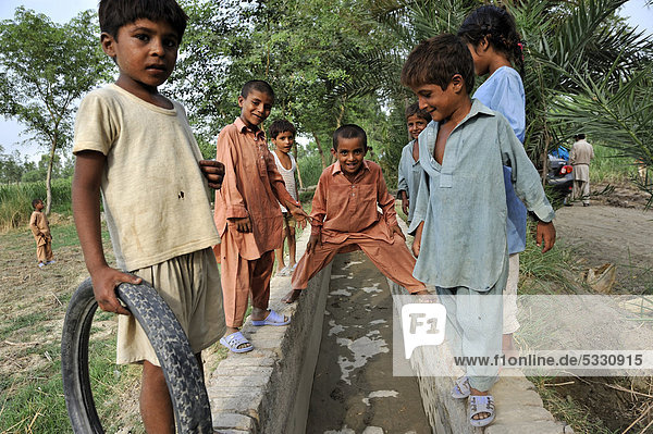 Children playing at an irrigation canal  Basti Lehar Walla village  Punjab  Pakistan  Asia