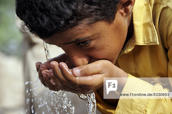 Boy  9  drinking water from the pump of a well  village of Moza Sabgogat near Muzaffaragarh  Punjab  Pakistan  Asia