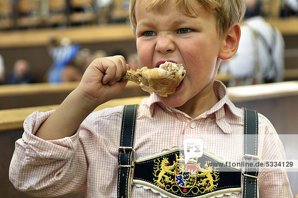 5jähriger Junge mit Lederhose sitzt im Bierzelt und ißt ein Hähnchen  Oktoberfest 2010  München  Oberbayern  Bayern  Deutschland  Europa
