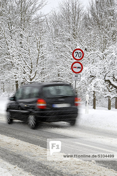 Verschneite Landstraße im Winter  Gebotsschild  Verbotsschild  Auto  Wischeffekt