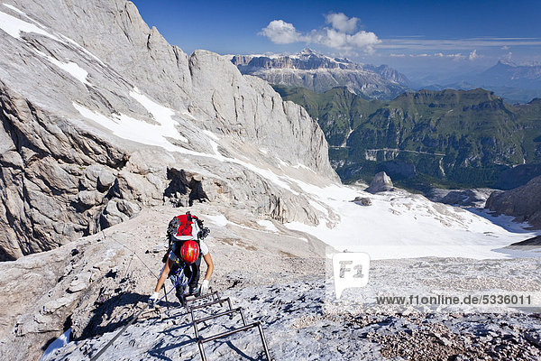 Mountaineer climbing Marmolada mountain  Dolomites  Westgrat fixed rope route  Sella alpenstock  Heiligkreuzkofel group and Fedaia pass at the back  province of Trento  Italy  Europe