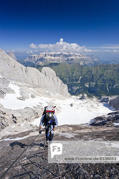 Bergsteiger beim Aufstieg zur Marmolata  Dolomiten  hinten der Sellastock sowie der Fedaiapass und der Fedaiasee  Klettersteig Westgrat  Trentino  Italien  Europa