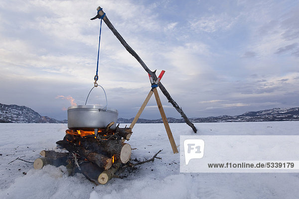 Kochen über Lagerfeuer mit hängendem Anheizherd oder Dutch Oven  Eis auf zugefrorenem Lake Laberge  Yukon Territory  Kanada