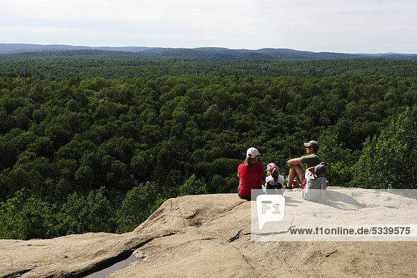 Family looking from a lookout point over the forested landscape of Algonquin Provincial Park  Ontario  Canada