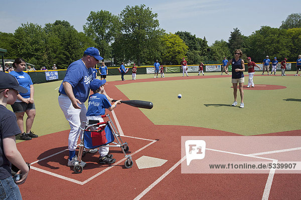 Behindertes Kind beim Baseball-Spielen in der Miracle League  Wunderliga  mit Kumpel  Freiwilligem  der dem Kind hilft  Southfield  Michigan  USA