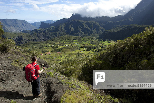 Hiker overlooking the remote and hard to reach mountain village of Marla  Cirque de Mafate caldera  La Reunion island  Indian Ocean