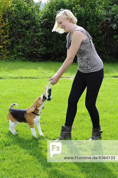 Junge Frau spielt im Freien mit einem Beagle