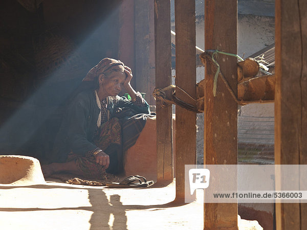 Alte Frau sitzt auf der Terrasse ihres Hauses  Chisapani  Helambu  Nepal  Asien
