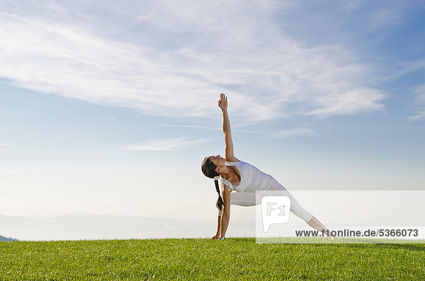 Junge Frau praktiziert Hatha-Yoga im Freien  zeigt die Stellung utthita parshvakonasana  Seitenstreckung  Nove Mesto  Okres Teplice  Tschechische Republik  Europa