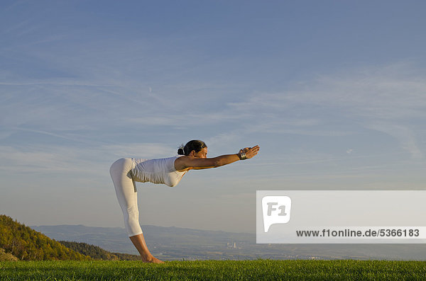 Junge Frau praktiziert Hatha-Yoga im Freien  zeigt die Stellung surya namaskar 4  Sonnengruß 4  Nove Mesto  Okres Teplice  Tschechische Republik  Europa