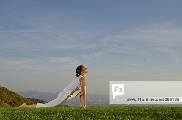 Junge Frau praktiziert Hatha-Yoga im Freien  zeigt die Stellung surya namaskar 6  Sonnengruß 6  Nove Mesto  Okres Teplice  Tschechische Republik  Europa