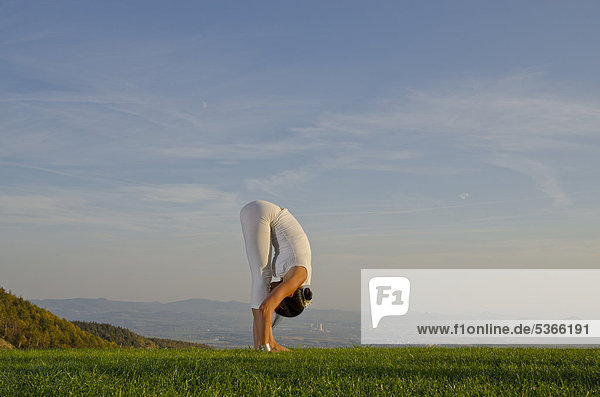 Junge Frau praktiziert Hatha-Yoga im Freien  zeigt die Stellung surya namaskar 12  Sonnengruß 12  Nove Mesto  Okres Teplice  Tschechische Republik  Europa