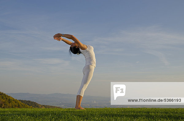 Junge Frau praktiziert Hatha-Yoga im Freien  zeigt die Stellung surya namaskar 14  Sonnengruß 14  Nove Mesto  Okres Teplice  Tschechische Republik  Europa