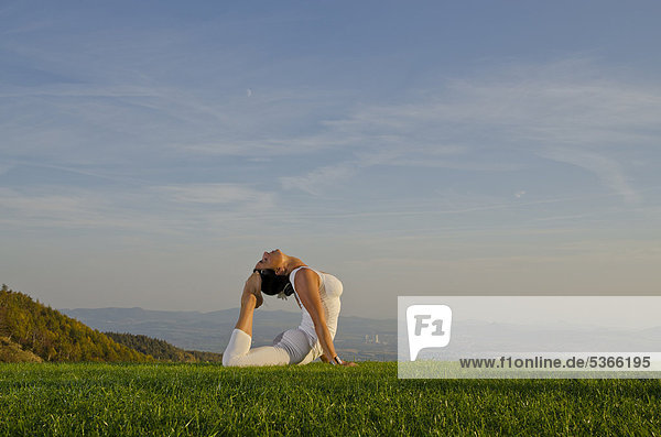 Junge Frau praktiziert Hatha-Yoga im Freien  zeigt die Stellung bhujangasana  Kobra  Nove Mesto  Okres Teplice  Tschechische Republik  Europa