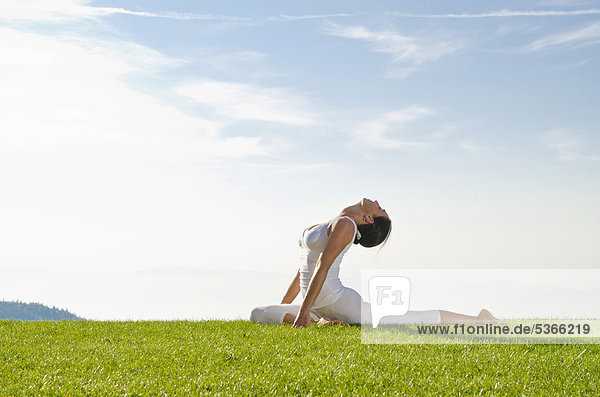 Junge Frau praktiziert Hatha-Yoga im Freien  zeigt die Stellung kapotasana  Taube  Nove Mesto  Okres Teplice  Tschechische Republik  Europa