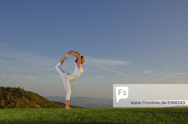 Junge Frau praktiziert Hatha-Yoga im Freien  zeigt die Stellung natarajasana  Tänzer  Nove Mesto  Okres Teplice  Tschechische Republik  Europa