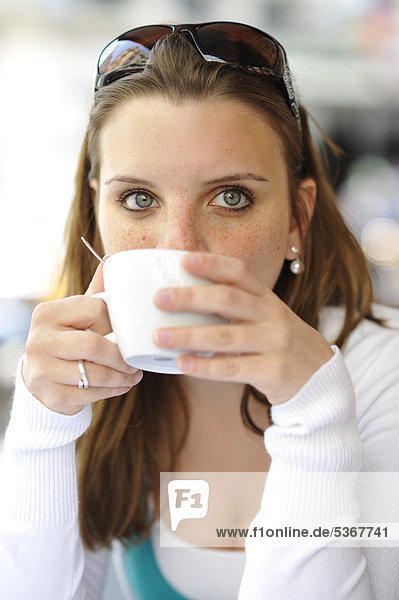 Young woman drinking coffee  holding coffee cup  cafe  Paris  France  Europe