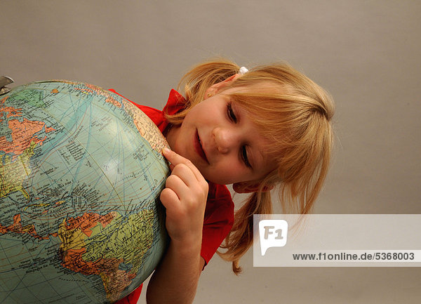 Kleines Mädchen  5 Jahre  schaut auf einen Globus