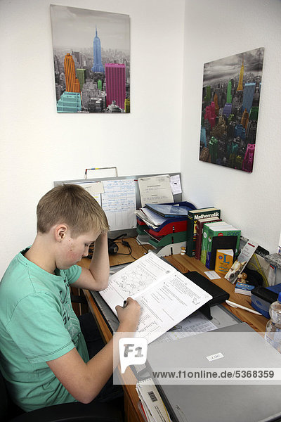 Boy  12 years  doing his homework in his room  studying for school