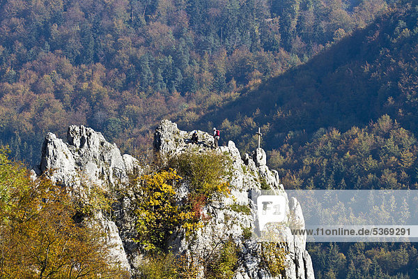 Climbers at the summit cross of Stuhlfels mountain  Upper Danube Nature Park  Sigmaringen district  Baden-Wuerttemberg  Germany  Europe