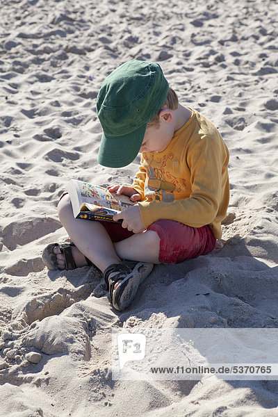 Kleiner Junge liest am Strand  Kühlungsborn-West  Mecklenburg-Vorpommern  Deutschland  Europa