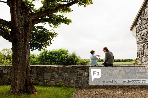 Vater und Sohn sitzen auf einer Steinmauer