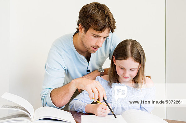Junger Mann Tochter bei Hausaufgaben helfen