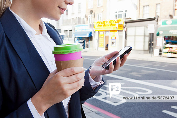 Schließung der Geschäftsfrau auf der Straße mit Kaffee und Smartphone