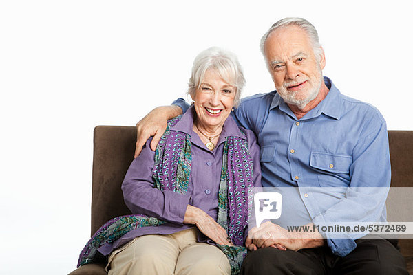 Senior couple on sofa against white background