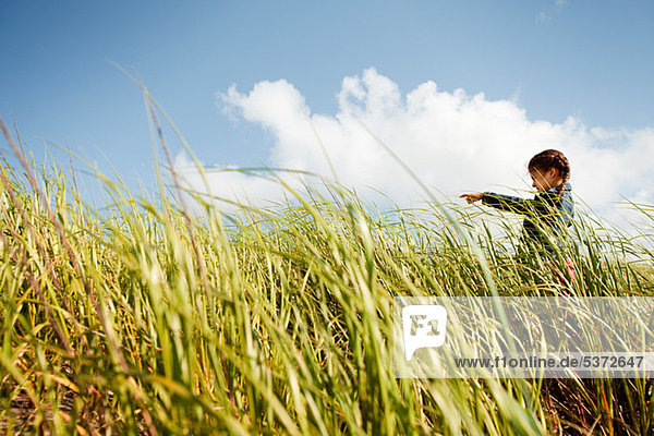 Girl pointing in long grass