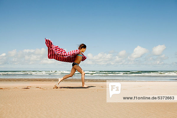 Girl running with blanket at beach