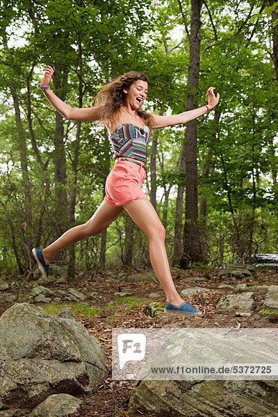 Young Hispanic Woman jumping über die Steine im Wald