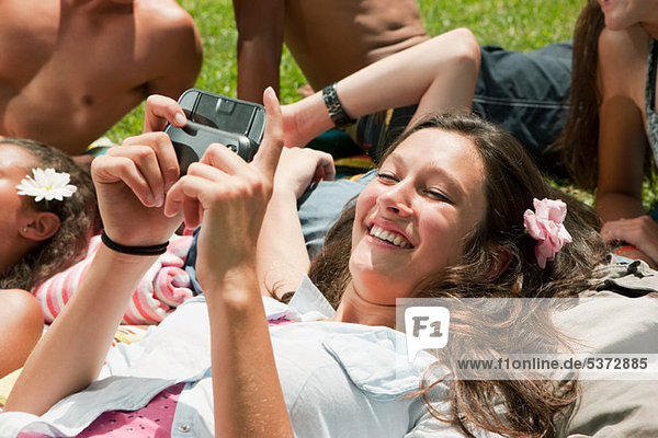 Teenage girl lying down with friends and looking at own camera pictures