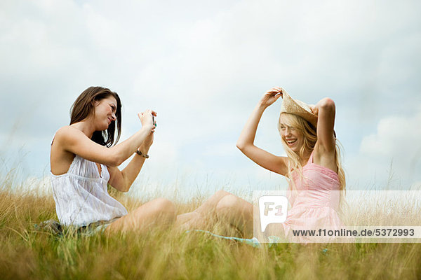 Junge Frau nehmen Foto eines Freundes posiert mit ein Sonnenhut
