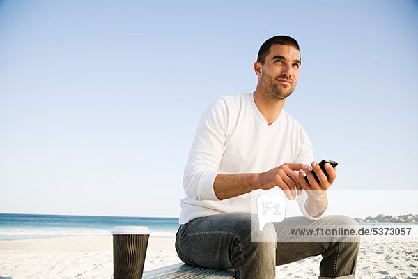 Mann mit Handy am Strand