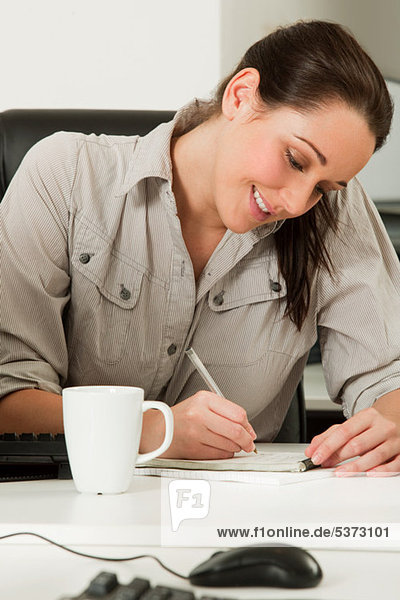 Weibliche Büroangestellter in ein Notizbuch schreiben