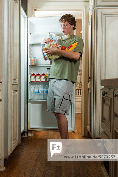 Teenager-Junge beim Essen aus dem Kühlschrank
