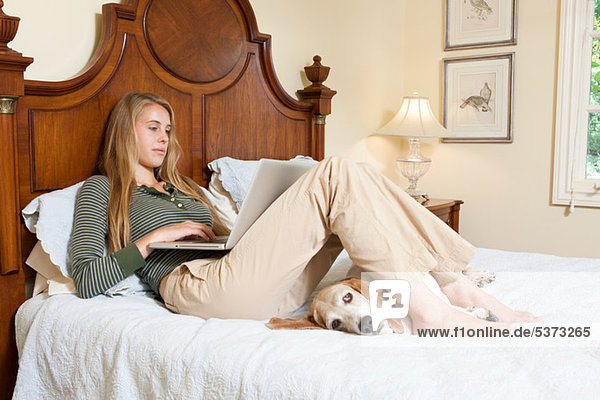 Young Woman relaxing auf Bett mit laptop