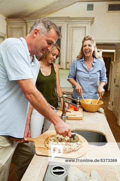 Family preparing pizza together in kitchen