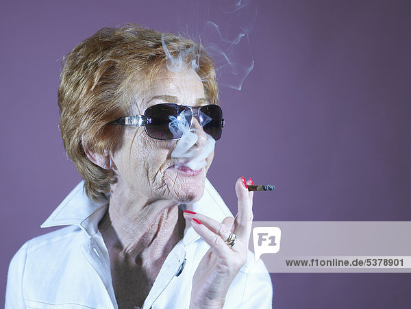 Seniorin raucht vor violettem Hintergrund