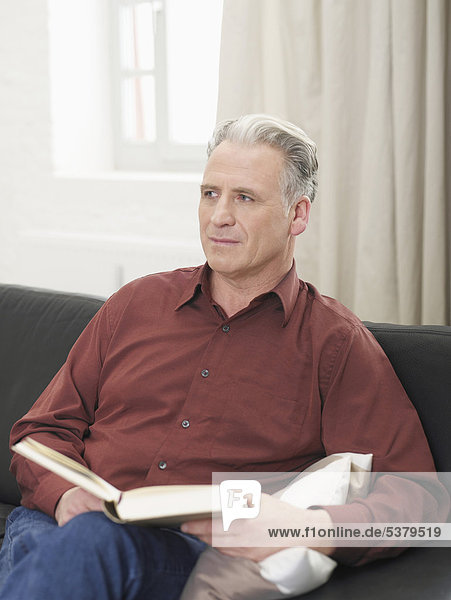 Senior man looking away with book