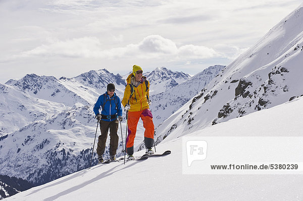Austria  Stuben  Young couple doing telemark skiing on arlberg mountain