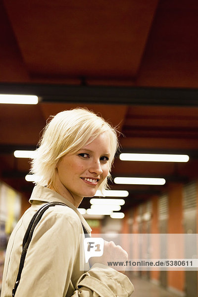 Young woman in metro station  smiling  portrait