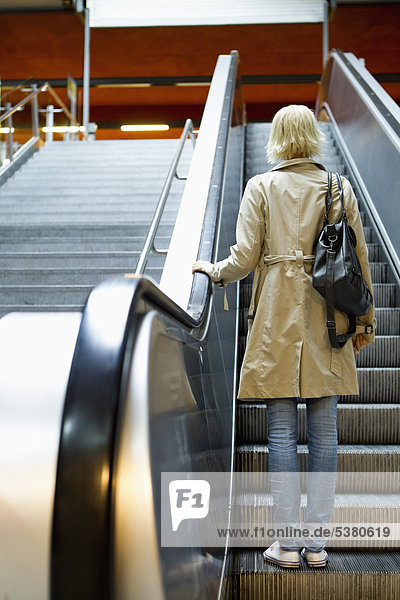 Junge Frau auf Rolltreppe in der U-Bahn-Station