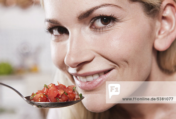 Italien  Toskana  Magliano  Junge Frau isst Löffel gehackte Tomaten  lächelnd