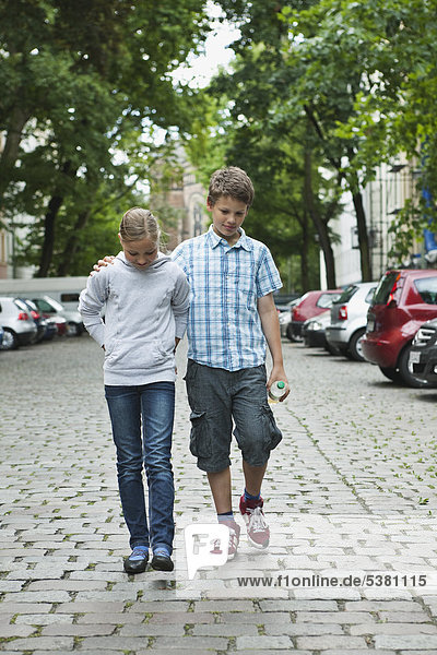 Junge und Mädchen gehen als Paar auf der Straße spazieren.