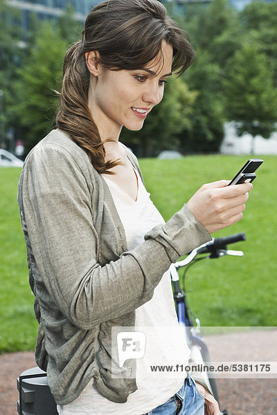 Woman using cell phone besides bicycle