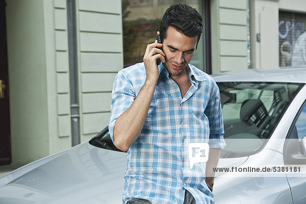 Man using cell phone in front of car